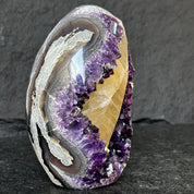 Amethyst geode on a dark surface with a gray background