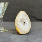 Geode crystal next to a wine glass on a dark surface
