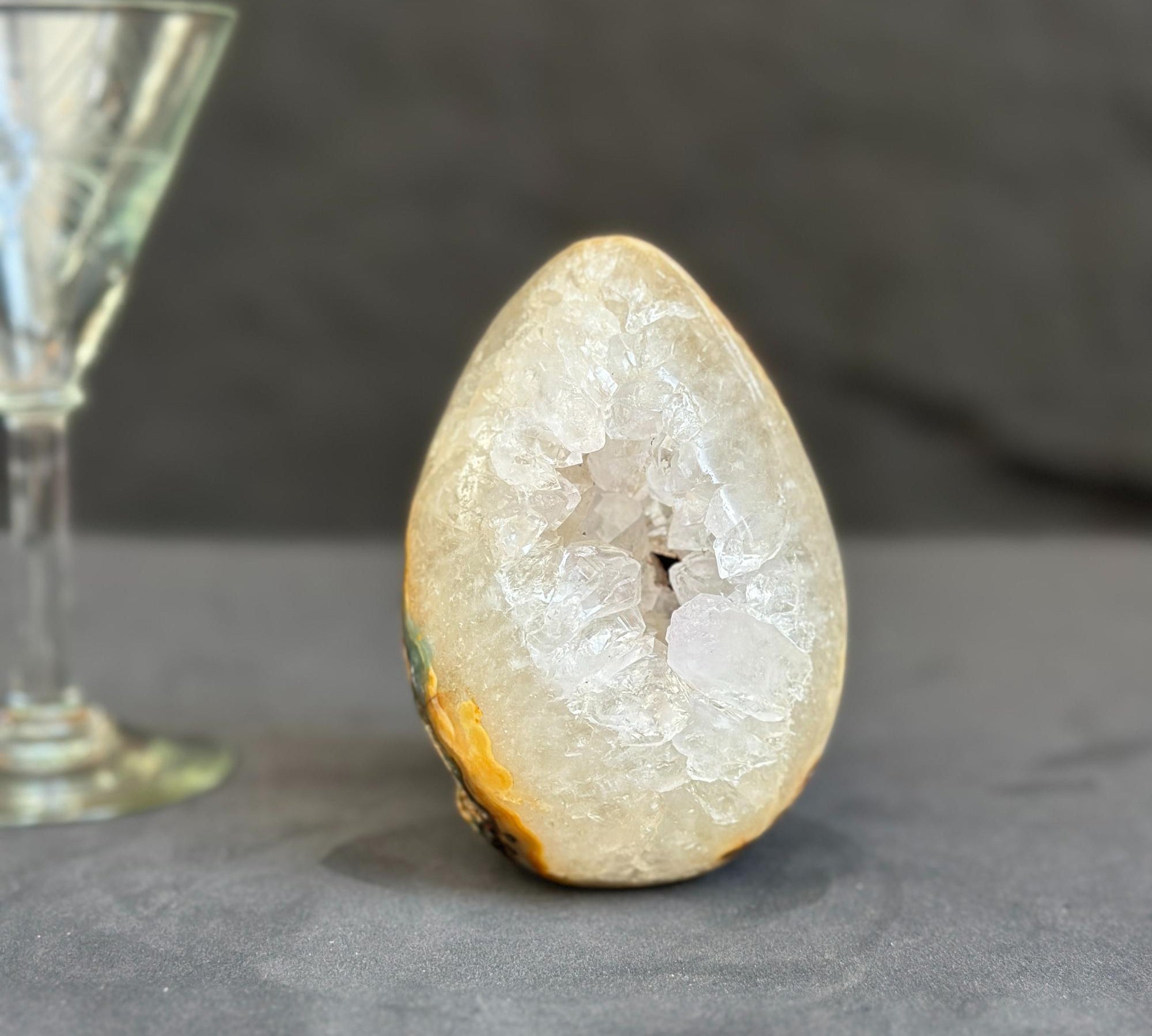 Geode crystal next to a wine glass on a dark surface