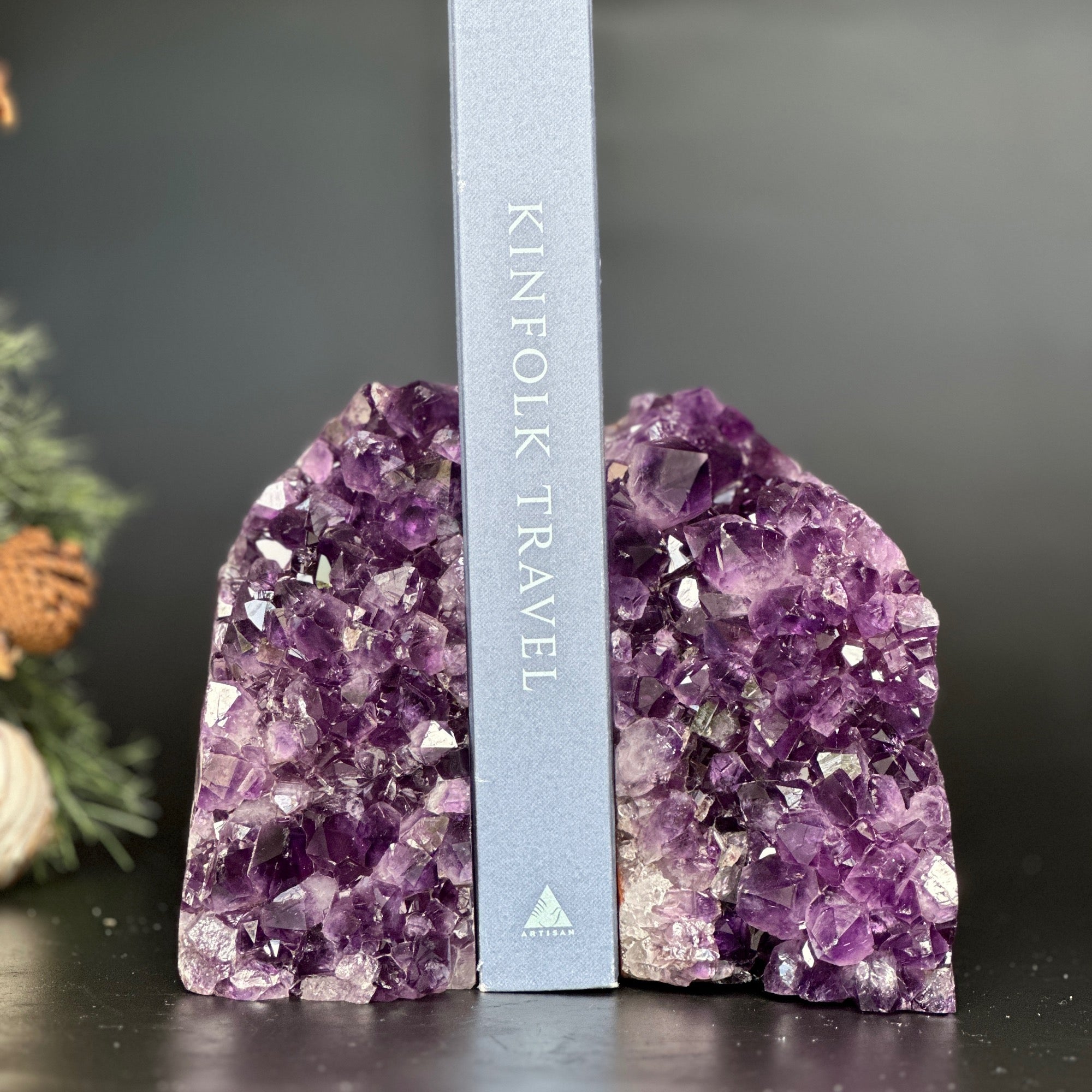 Supersized deep purple amethyst geode bookends holding a gray book.