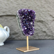 Extra large, natural deep purple amethyst crystal geode on a gold metal stand.