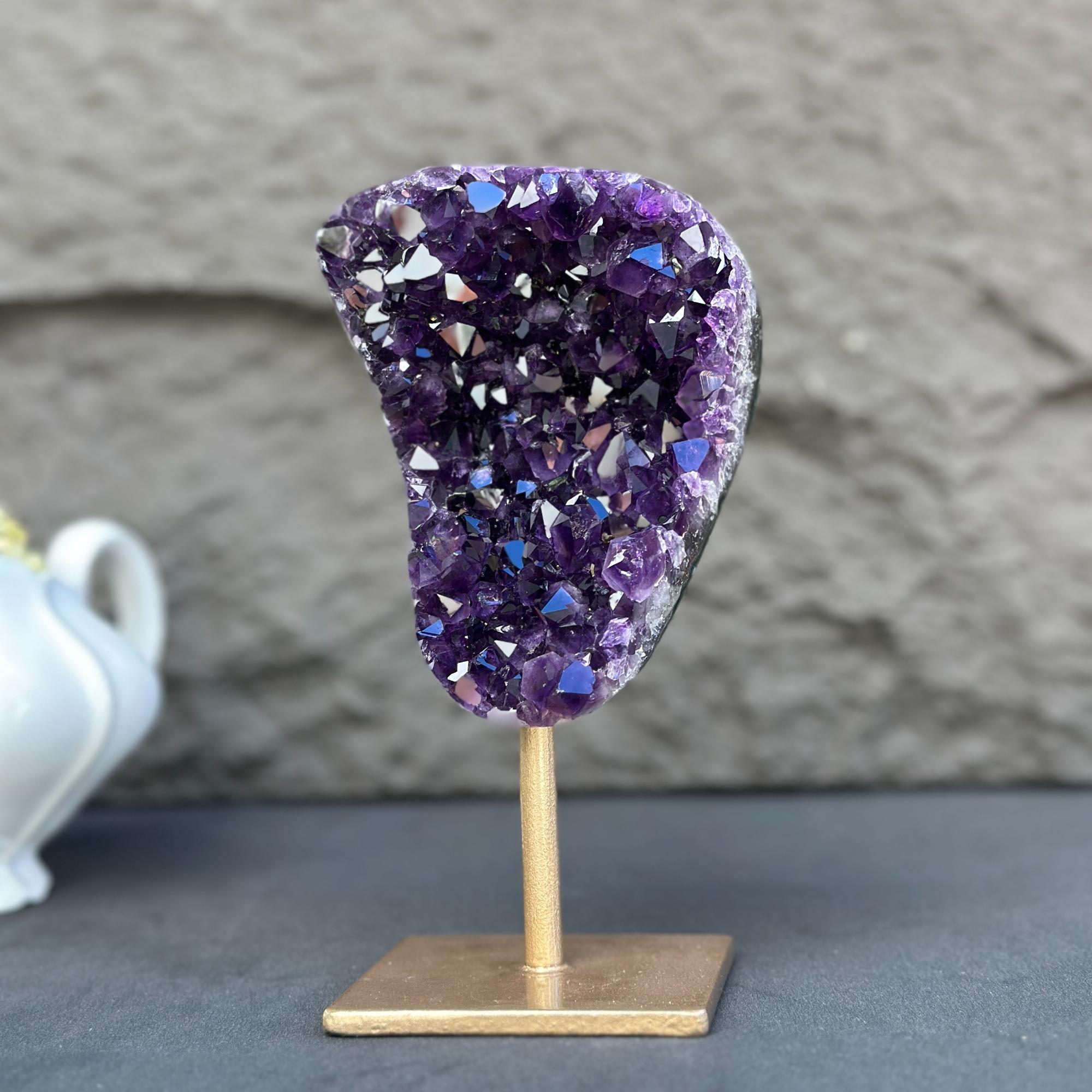 Extra large natural deep purple amethyst crystal geode on a gold metal stand.
