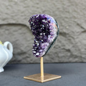 Extra large, natural deep purple amethyst crystal geode on a gold metal stand.