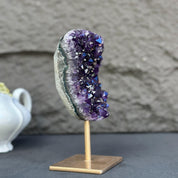 Extra large, natural purple amethyst crystal geode on a gold metal stand.