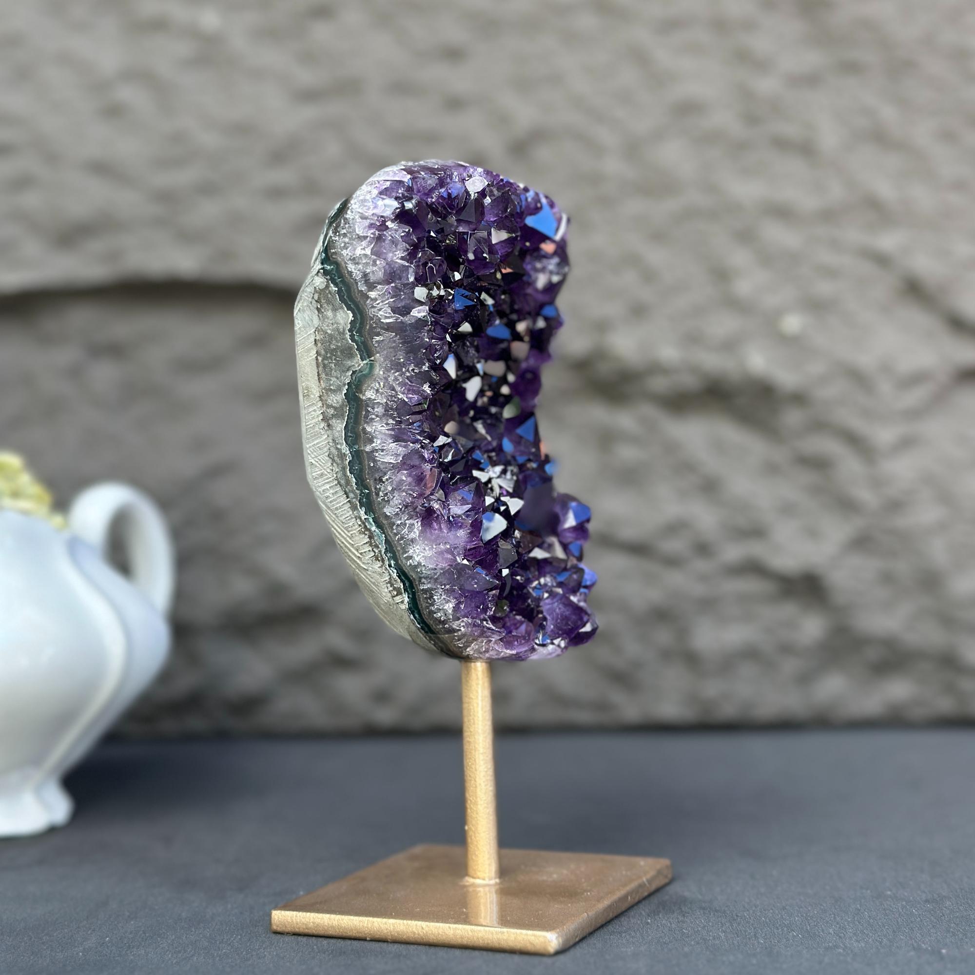 Extra large, natural purple amethyst crystal geode on a gold metal stand.
