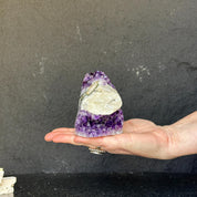 Rare amethyst crystal cathedral with polished edges, held in a hand.
