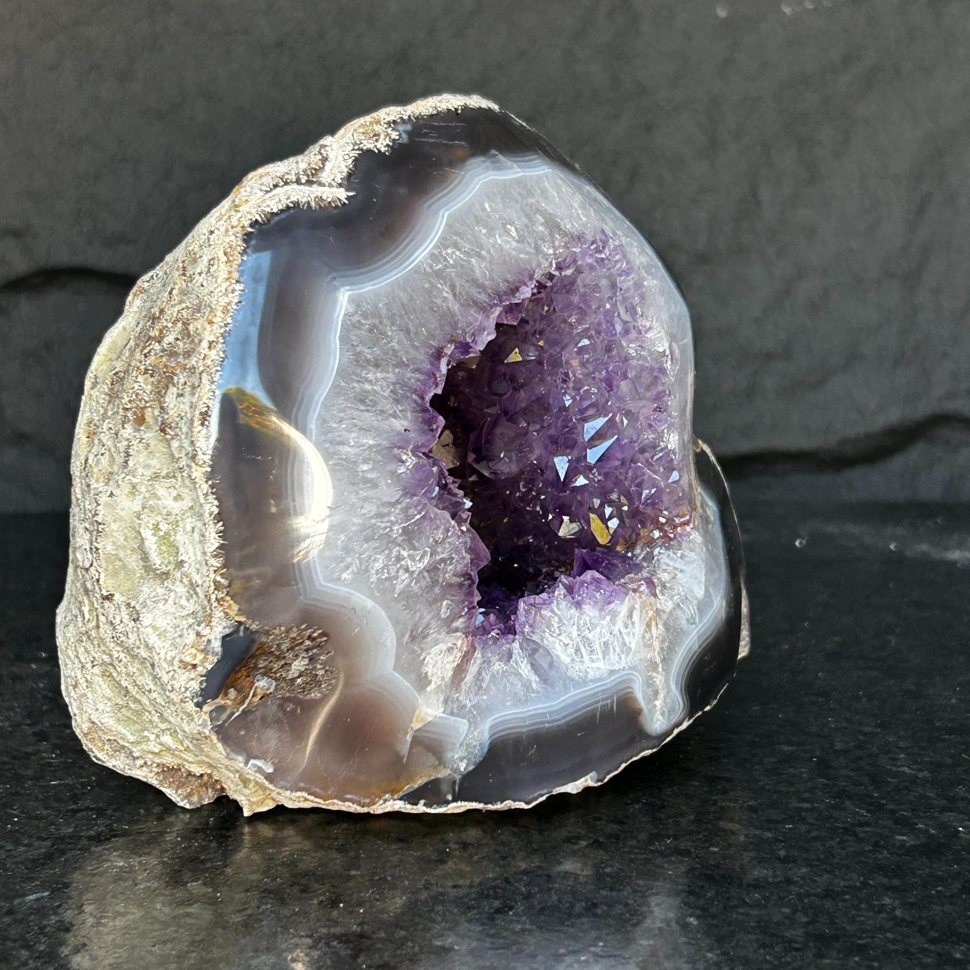 Extra large Uruguayan amethyst geode with deep purple crystals and striking agate edges.
