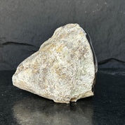 Rough, unpolished amethyst geode exterior with natural rock texture and dark agate edges.