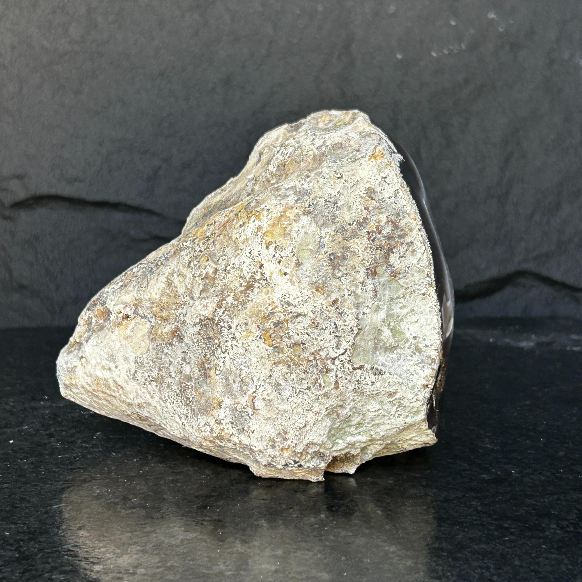 Rough, unpolished amethyst geode exterior with natural rock texture and dark agate edges.