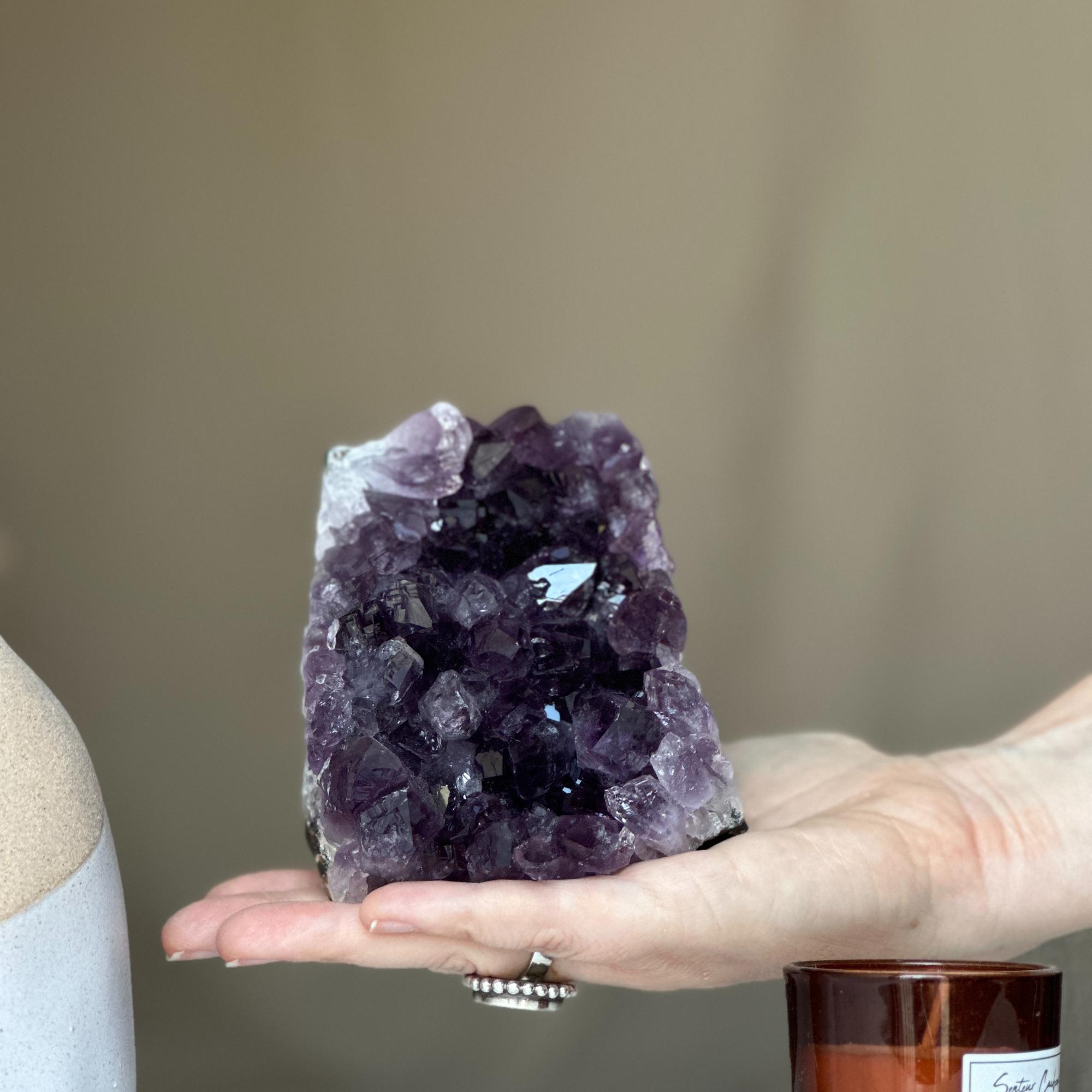 Hand holding a large, deep purple Amethyst geode cluster from Uruguay, 3.5x4 inches.
