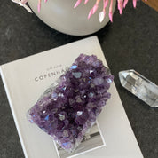 Vibrant purple amethyst and agate cluster, 4.5" tall, on a white book with a clear quartz point.