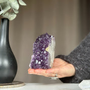 Hand holding a vibrant purple amethyst cathedral geode, a unique self-standing crystal cluster.