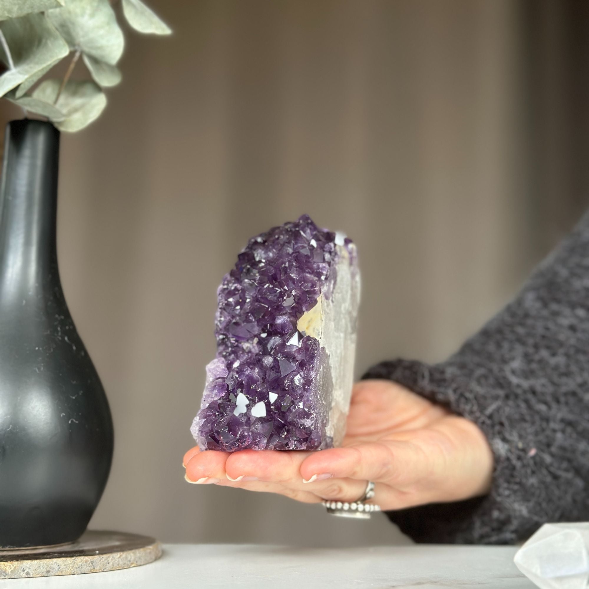 Hand holding a vibrant purple amethyst cathedral geode, a unique self-standing crystal cluster.