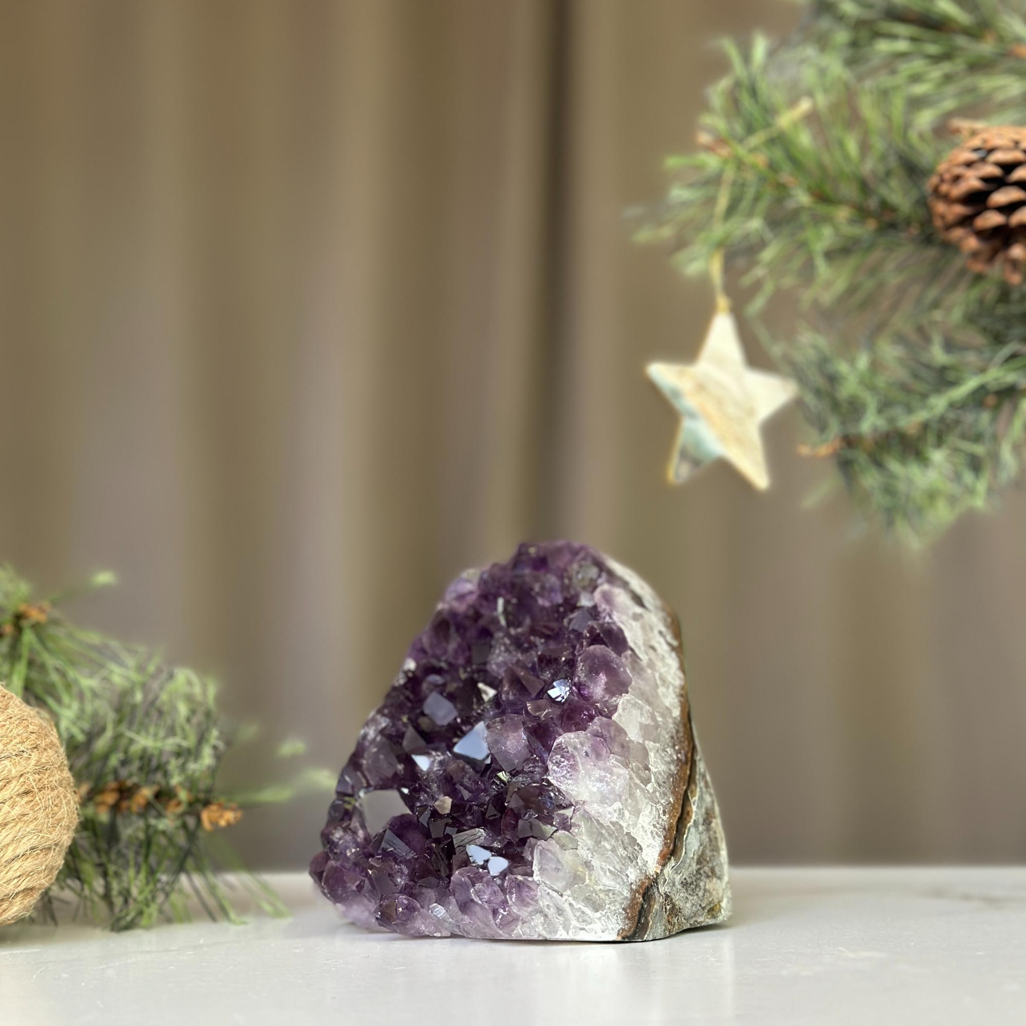 Deep purple Uruguayan amethyst cathedral geode, 3x3 inches, on a white surface with pine branches.