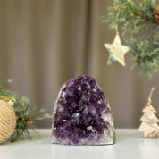 Deep purple Uruguayan amethyst cathedral geode, 3x3 inches, on a white surface with festive pine branches.