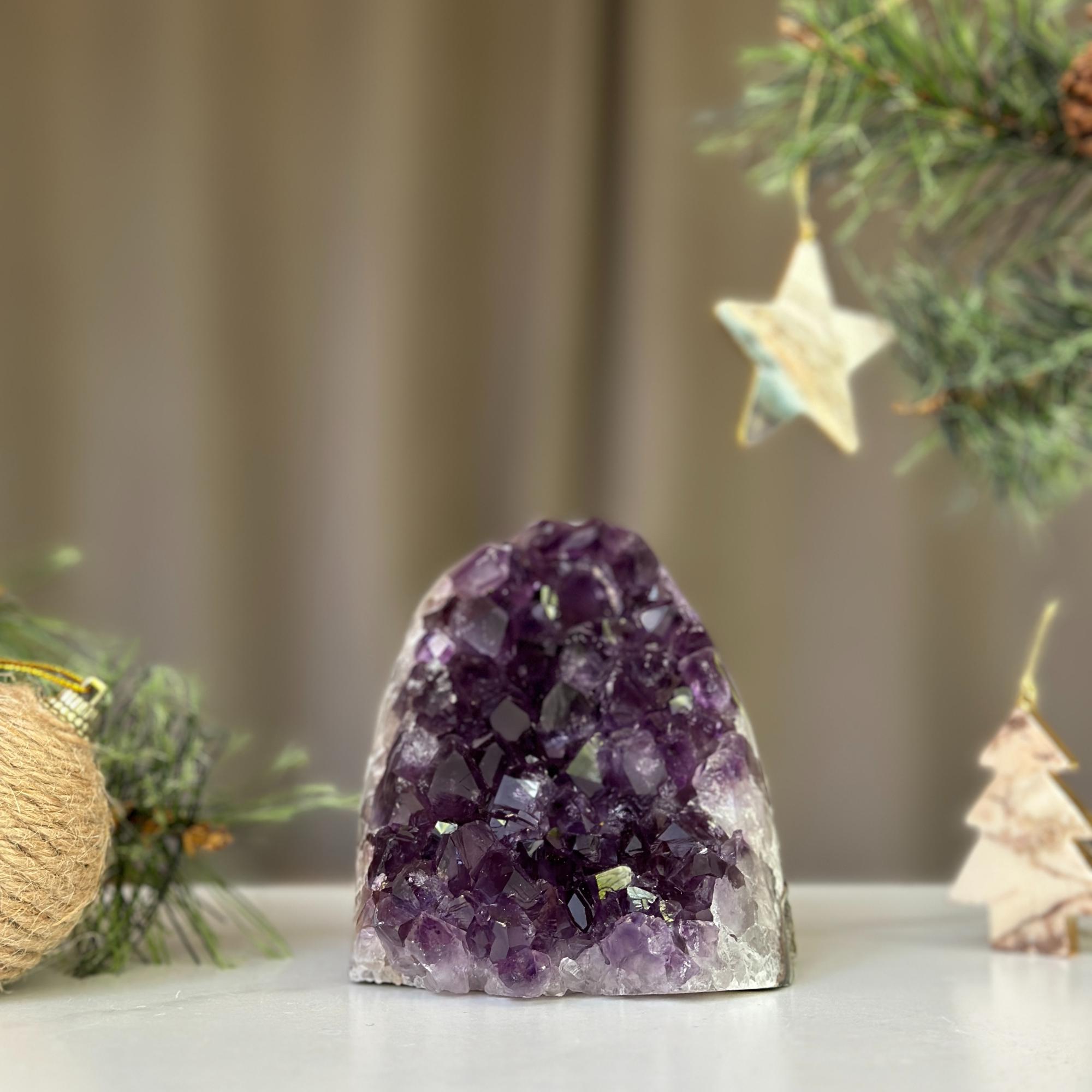 Deep purple Uruguayan amethyst cathedral geode, 3x3 inches, on a white surface with festive pine branches.