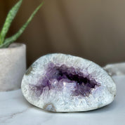 Polished amethyst geode cave with deep purple crystals and white agate edges.