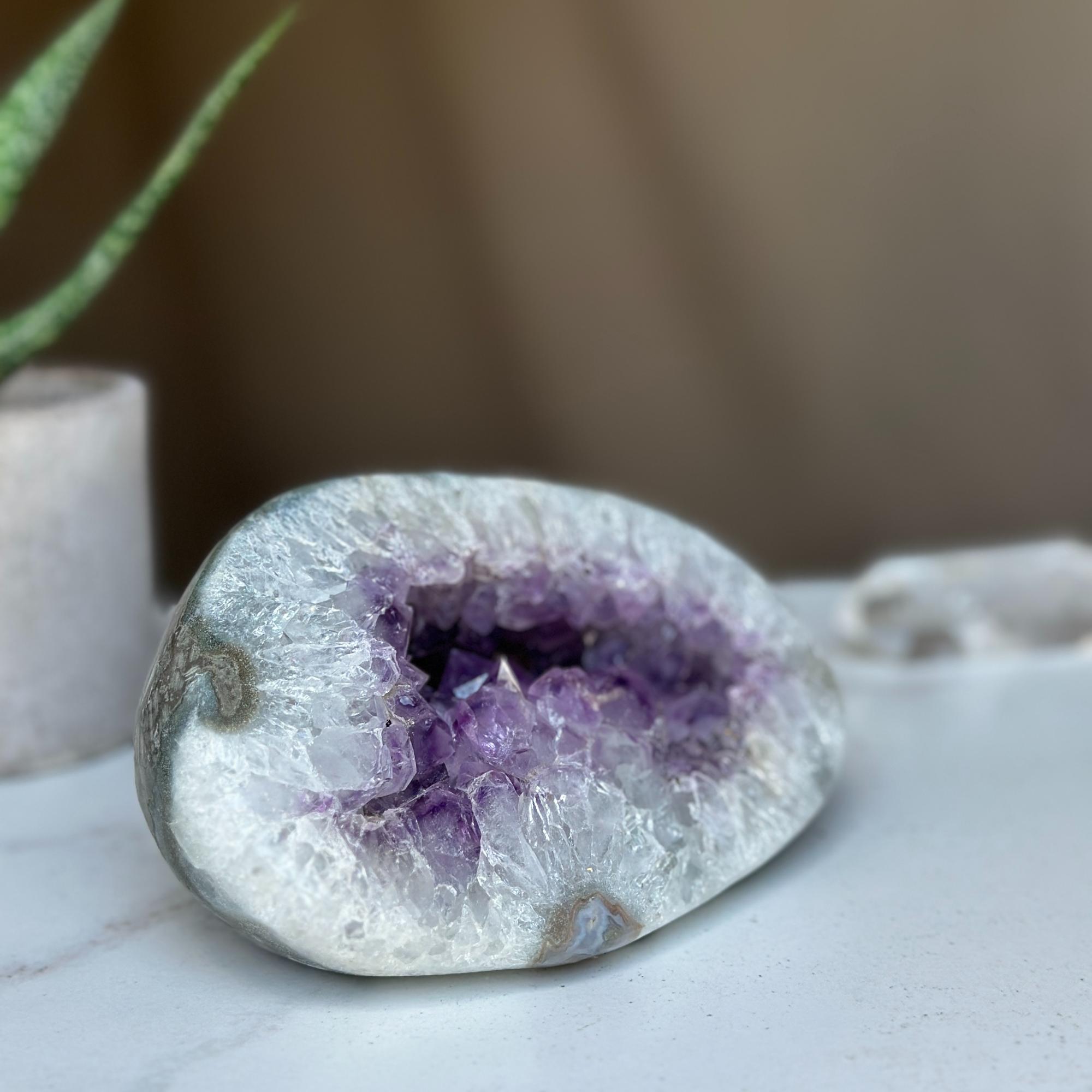 Polished amethyst geode cave with deep purple crystals and natural gray-white agate edges.