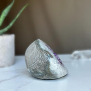 Polished amethyst geode cave with deep purple crystals and gray agate edges.