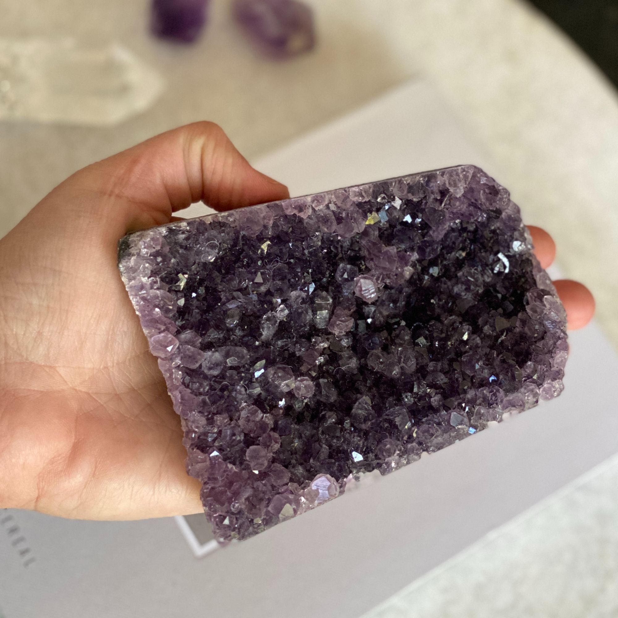 Hand holding a vibrant deep purple amethyst crystal geode cluster, 3x4.3 inches.