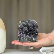 Hand holds a sparkling deep purple amethyst geode cluster with dark rough matrix. Natural 2.5x4 inch semi-precious stone.