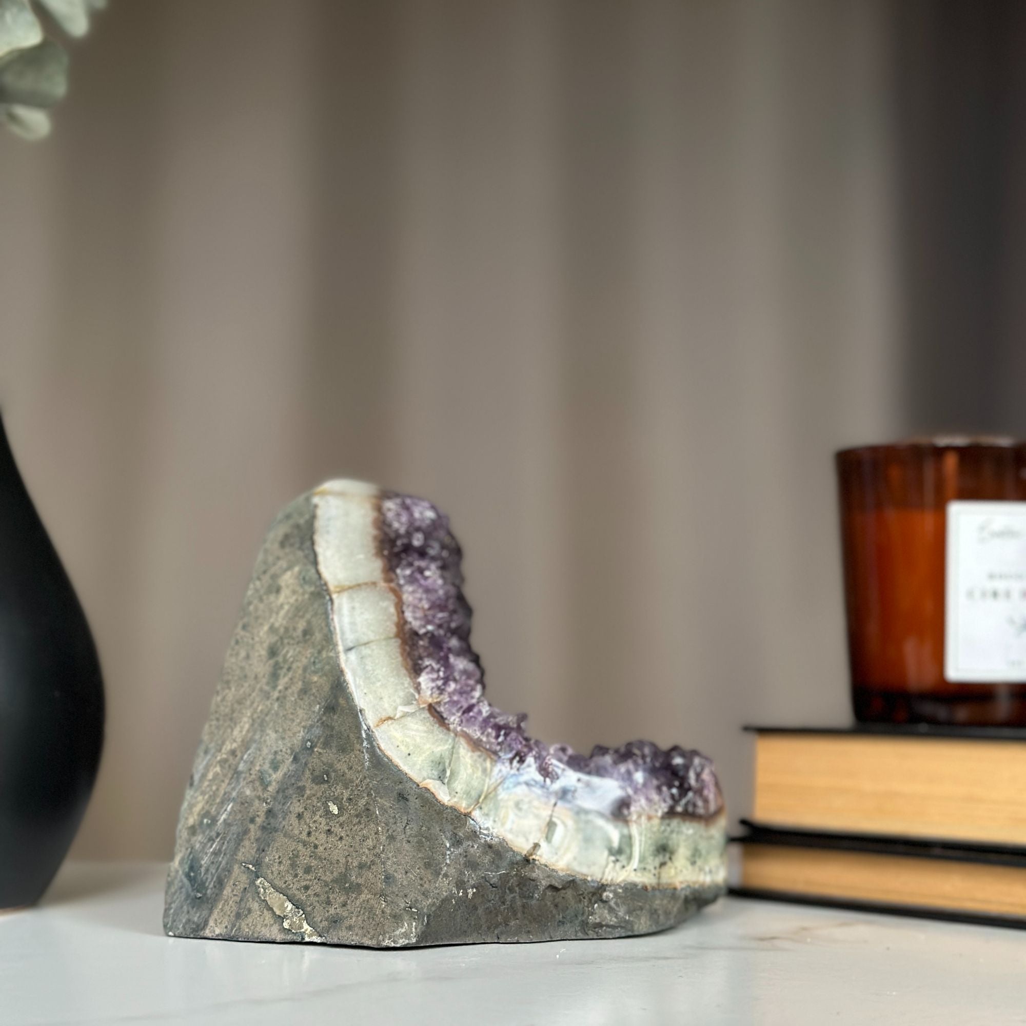 Large, sparkling purple amethyst cluster with huge crystals, raw stone base, on a white surface.