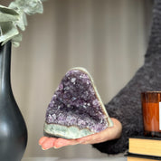 Large, sparkling purple amethyst cluster with huge crystals, held by a hand.
