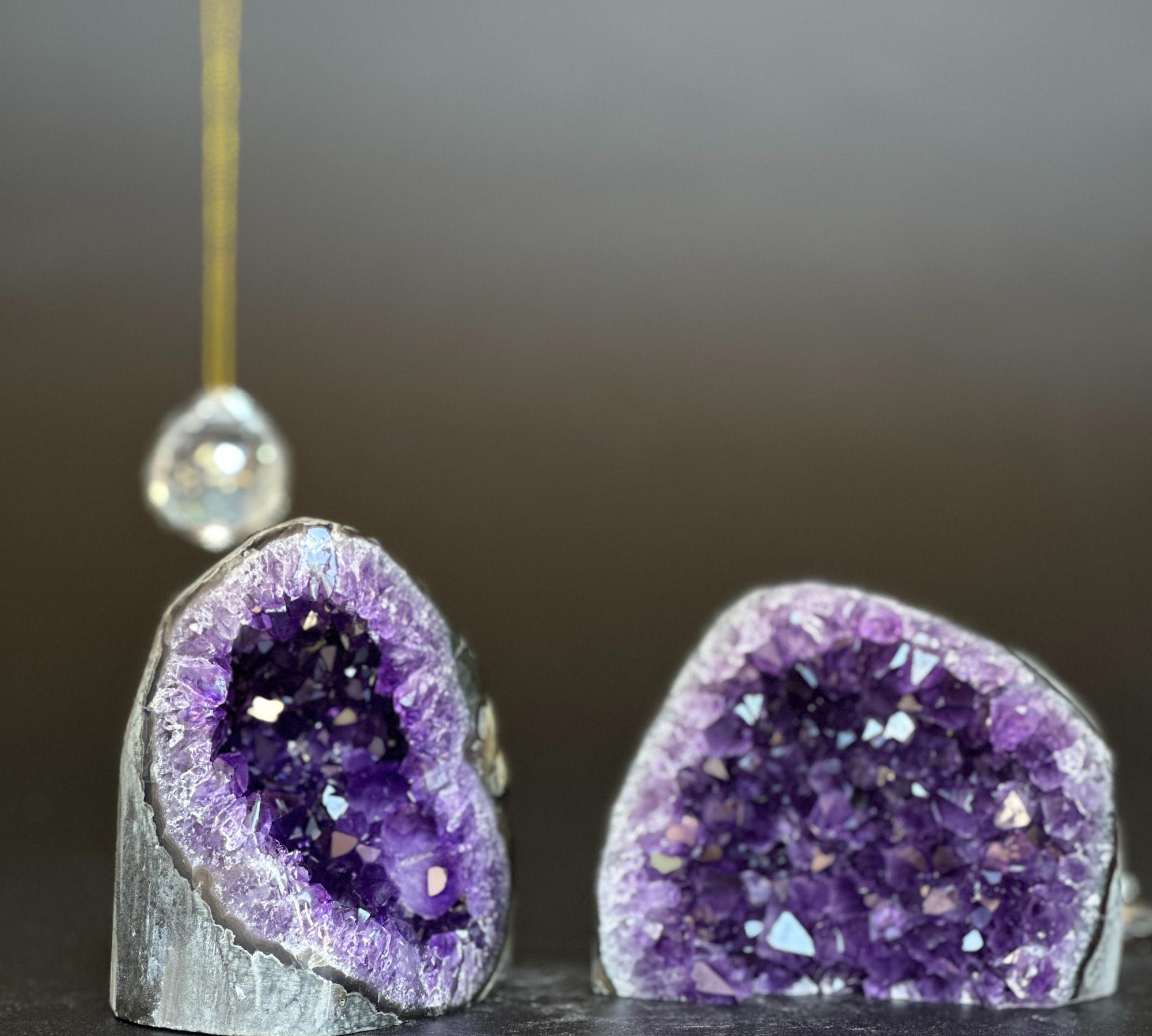 Two deep purple amethyst clusters with white agate layers, one on left with a crystal ornament.