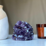 Large vibrant deep purple amethyst geode crystal cluster with sparkling facets.