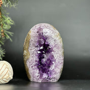 Vibrant deep purple amethyst geode egg with sparkling crystals and natural agate edges.