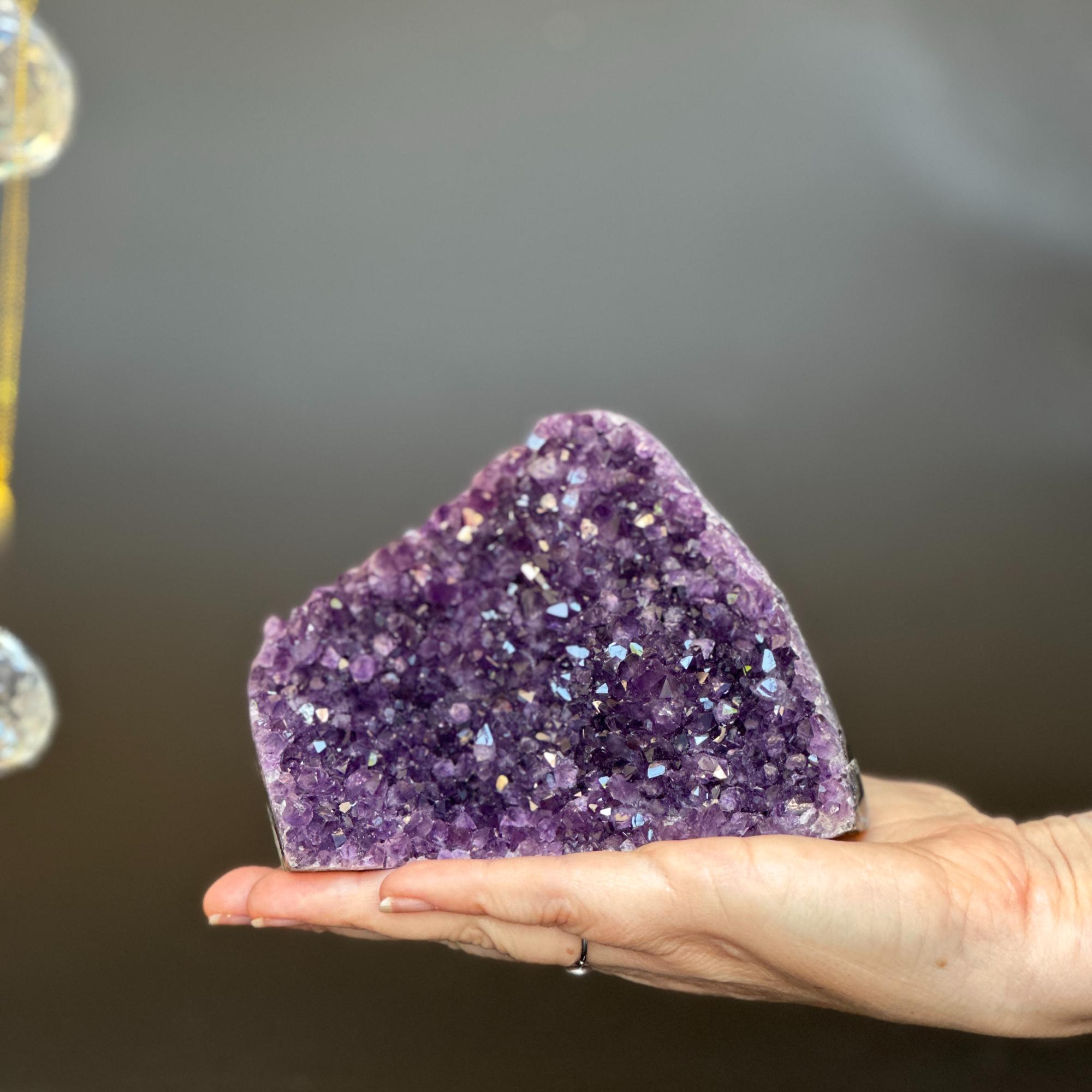 Hand holding a vibrant deep purple Uruguayan amethyst geode crystal cluster, 4.5x4 inches.