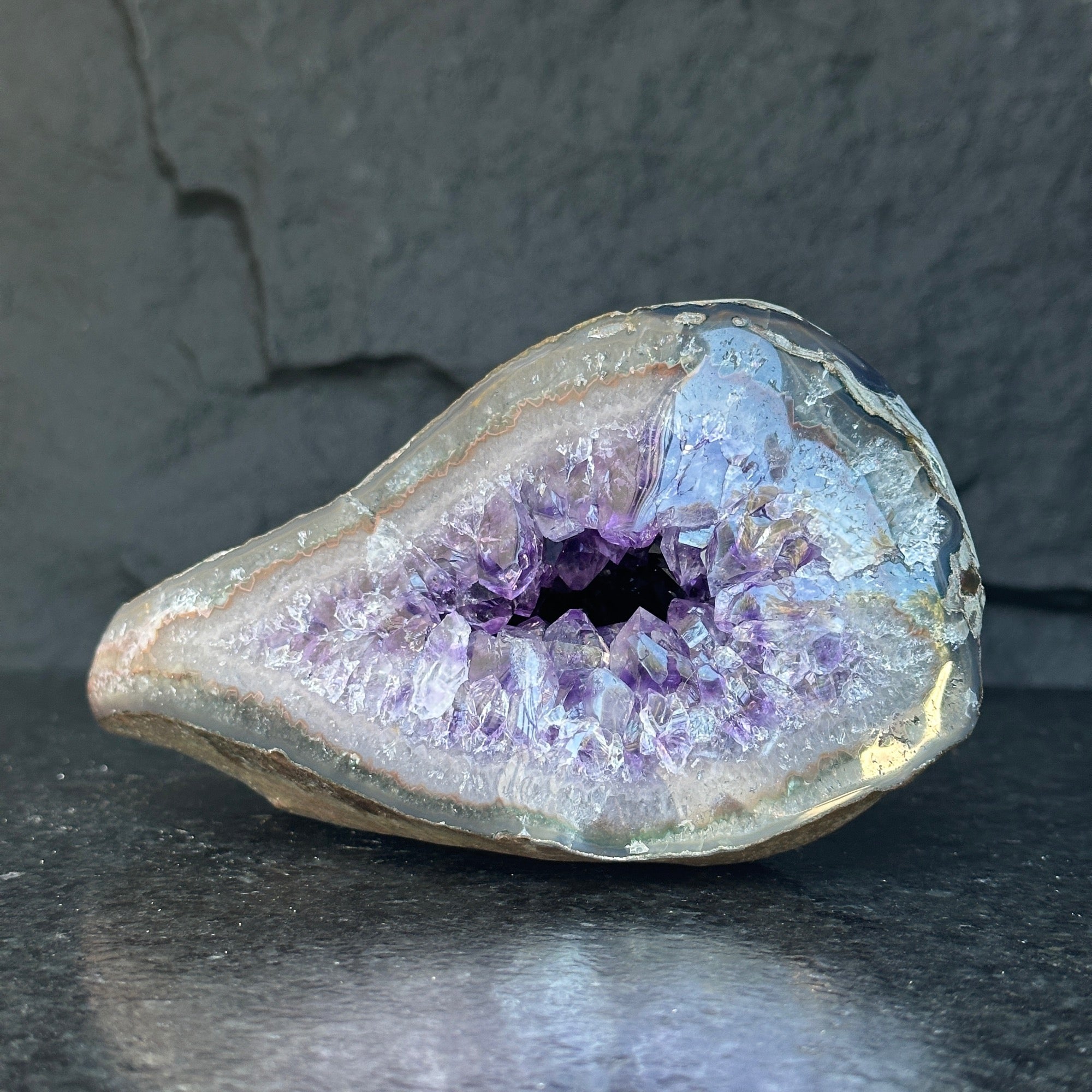 Sparkling deep purple amethyst geode from Uruguay, featuring natural crystal formations and a self-standing base.