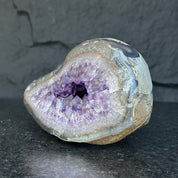 Self-standing Uruguayan amethyst geode with sparkling deep purple crystals and a natural gray-brown rock exterior.