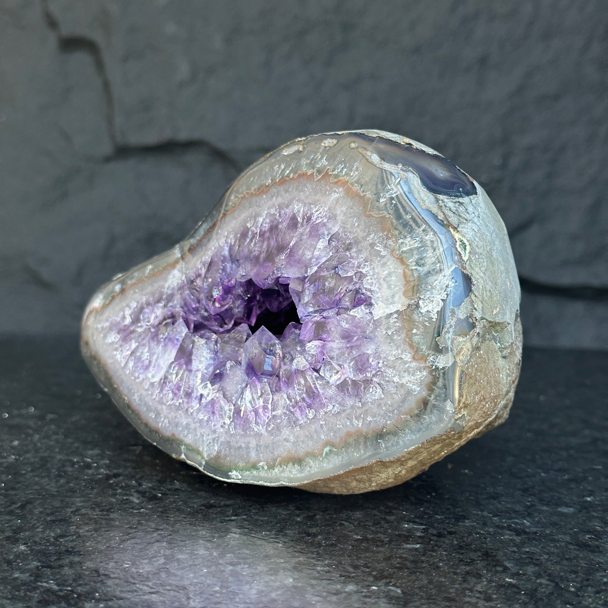 Self-standing Uruguayan amethyst geode with sparkling deep purple crystals and a natural gray-brown rock exterior.