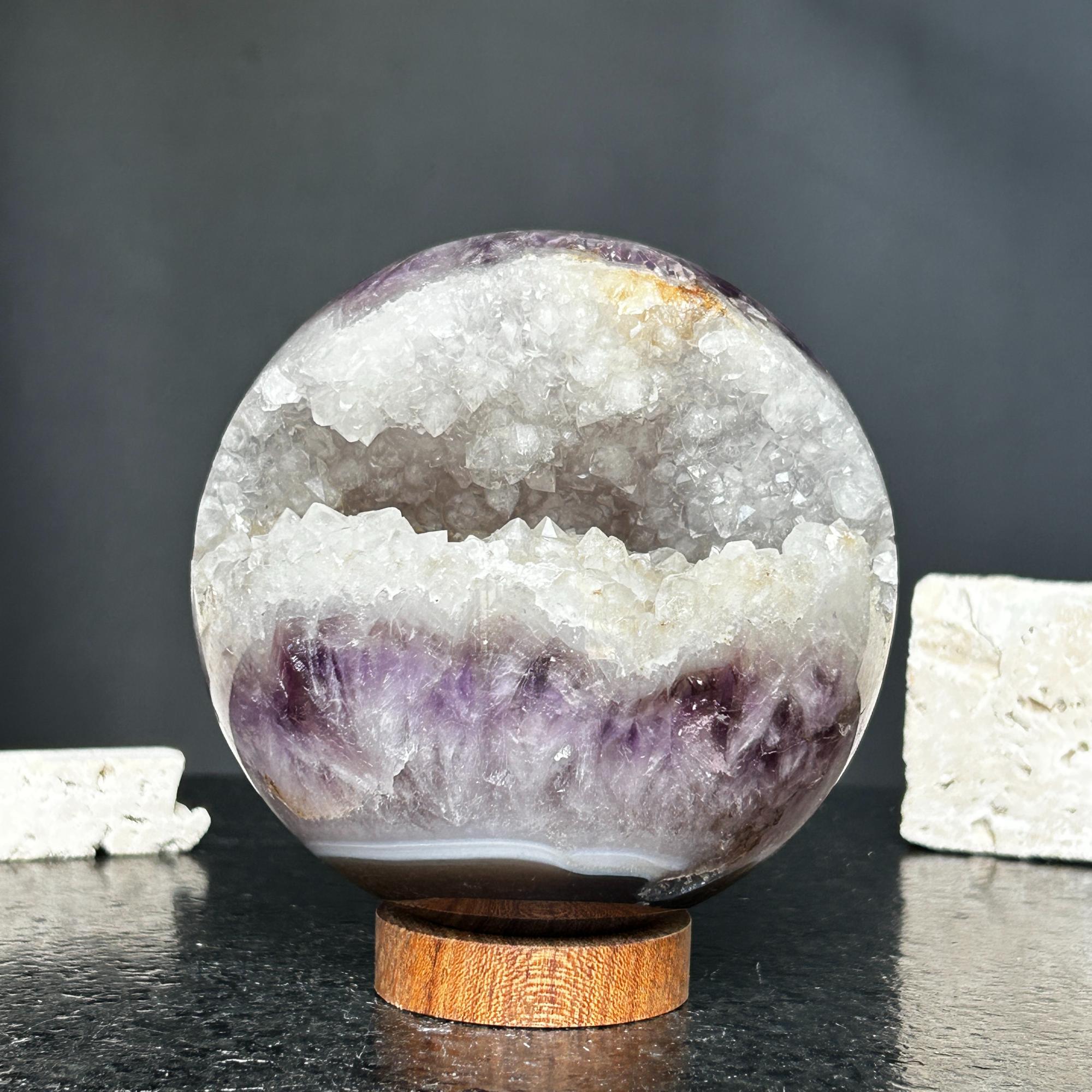 4-inch amethyst geode sphere with sparkling purple crystals and white quartz interior, resting on a round carob wood base.