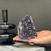 Deep purple Uruguayan cathedral amethyst raw stone, 4-inch tall crystal cluster held in a hand.