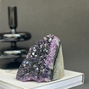 Vibrant deep purple Uruguayan cathedral amethyst raw stone cluster, 4-inch tall, on a book.