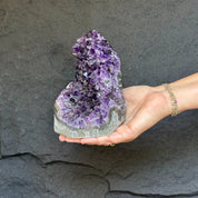 Extra large, deep purple amethyst geode cathedral with agate formations, held in a hand.