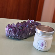 Amethyst crystal cluster with a small jar labeled 'Deeppurple' on a neutral surface.