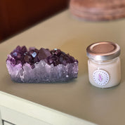 Amethyst crystal and a candle on a wooden surface