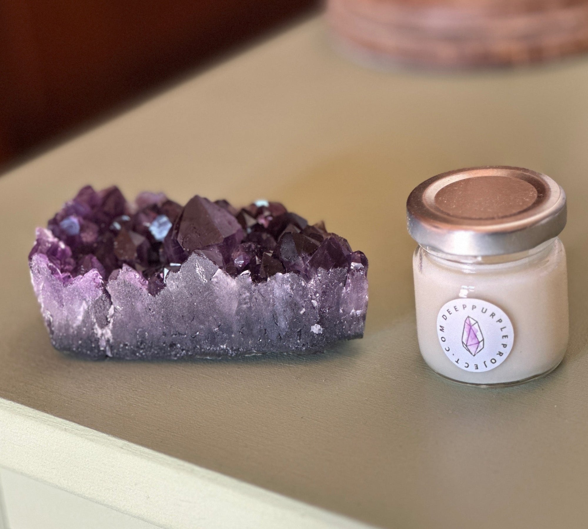 Amethyst crystal and a candle on a wooden surface