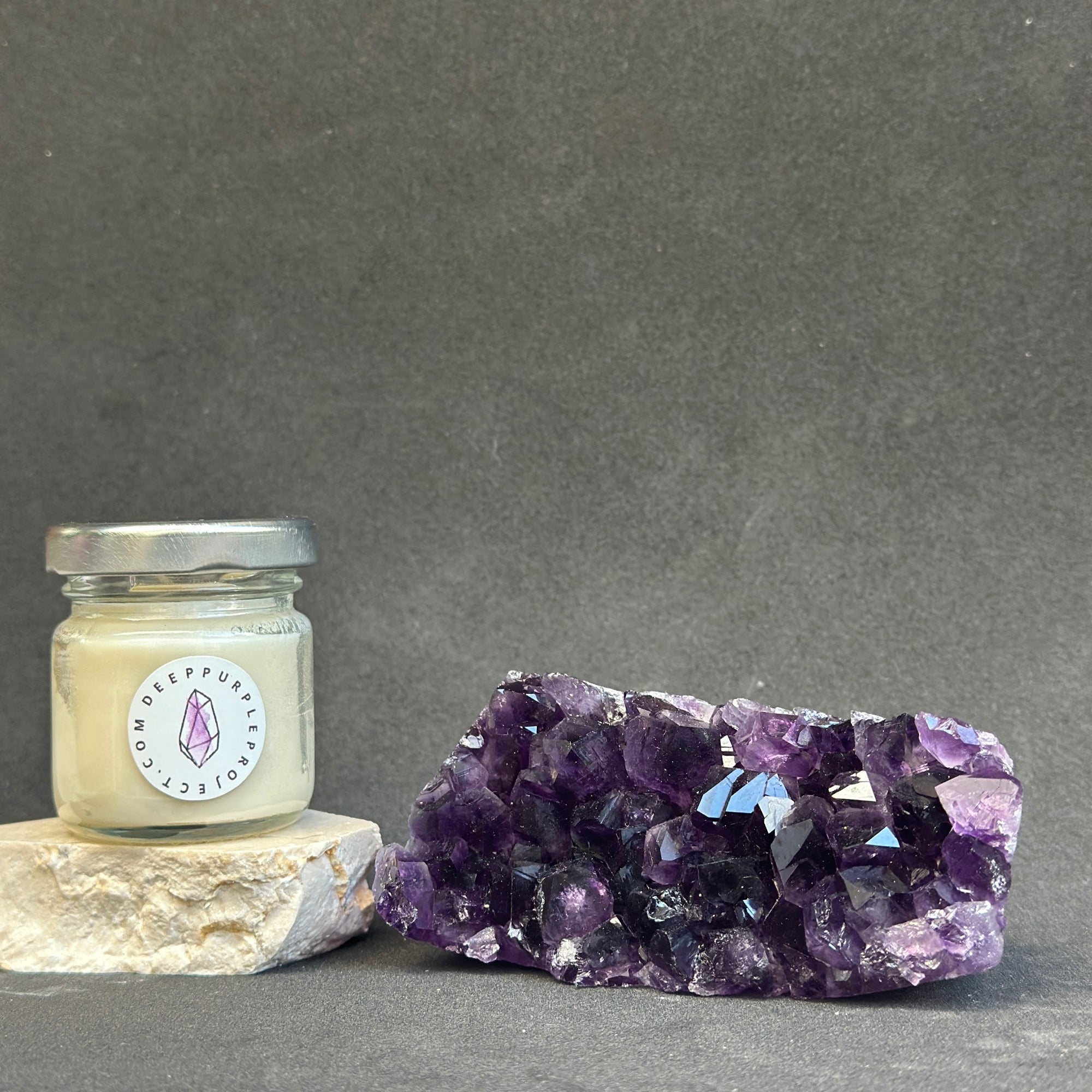 Jar of candle with a purple crystal on a gray background