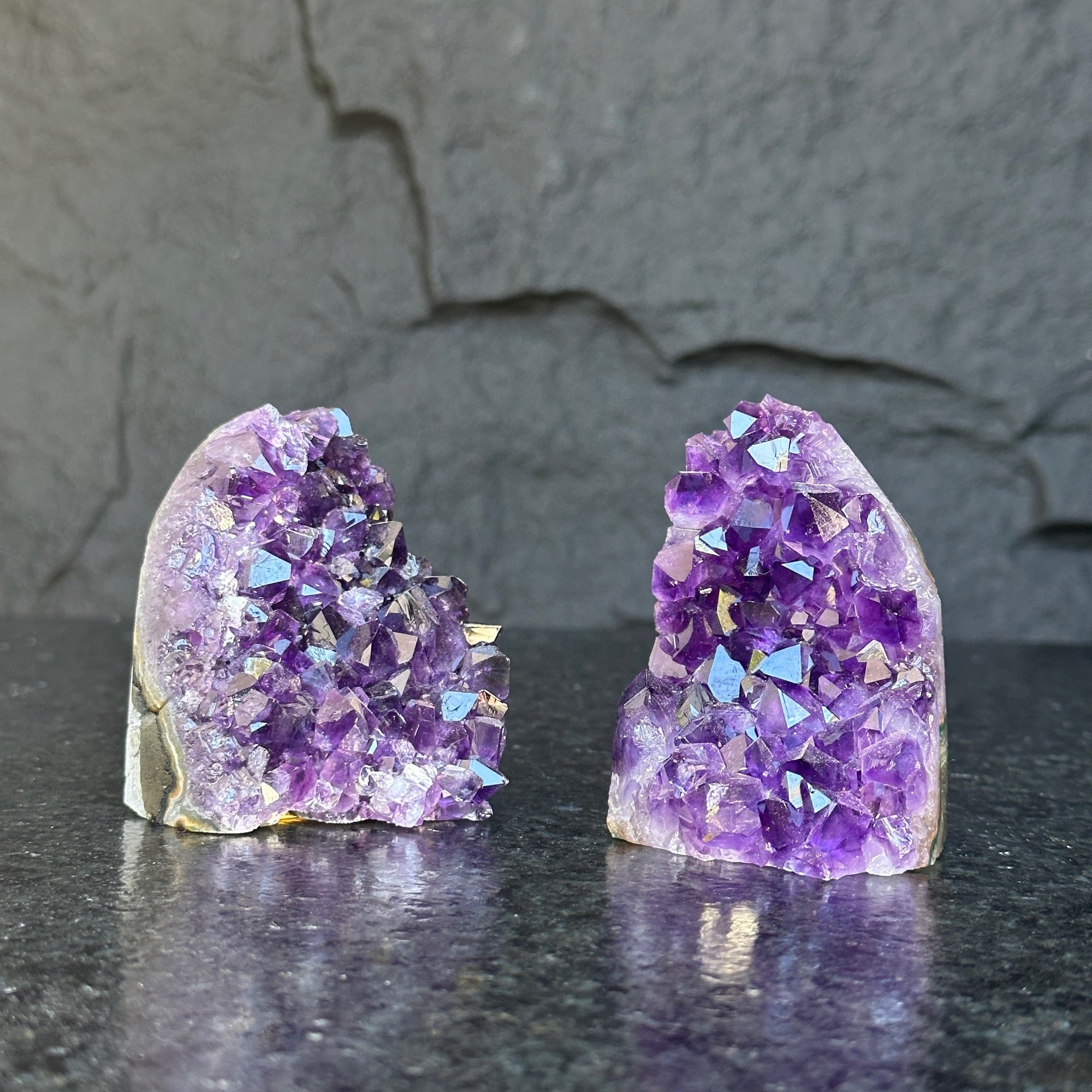 Two raw, deep purple Uruguayan amethyst geode clusters, 3-inch tall, on a dark surface.