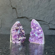 Two raw Uruguayan amethyst geode clusters, deep purple, 3-inch high, on a dark surface.