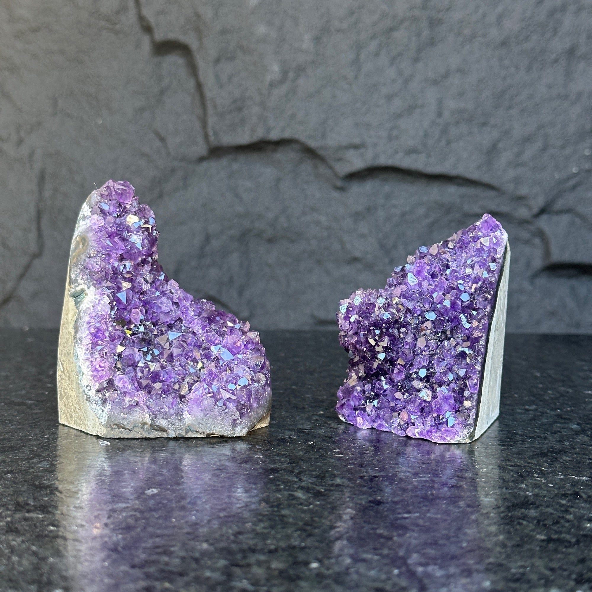 Two raw, deep purple Uruguayan amethyst geode clusters, 3-inch high, on a dark surface.