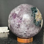 Polished purple amethyst sphere, 4-inch, with internal crystals, dark green agate & jasper on a wood base.