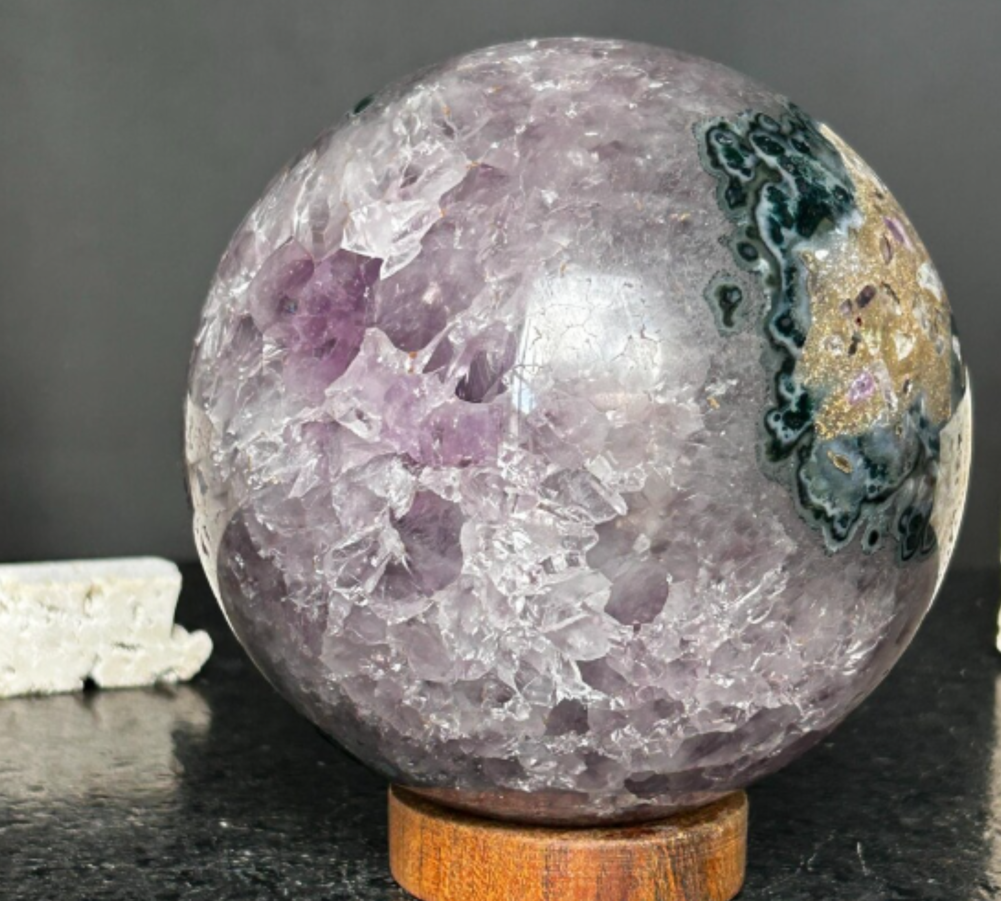 Polished purple amethyst sphere, 4-inch, with internal crystals, dark green agate & jasper on a wood base.