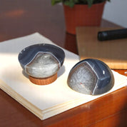 Two sphere-shaped agate paperweights on top of a wooden stand, placed on a desk next to a stack of papers.