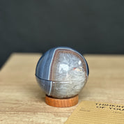 Polished stone sphere on a wooden surface with a dark background
