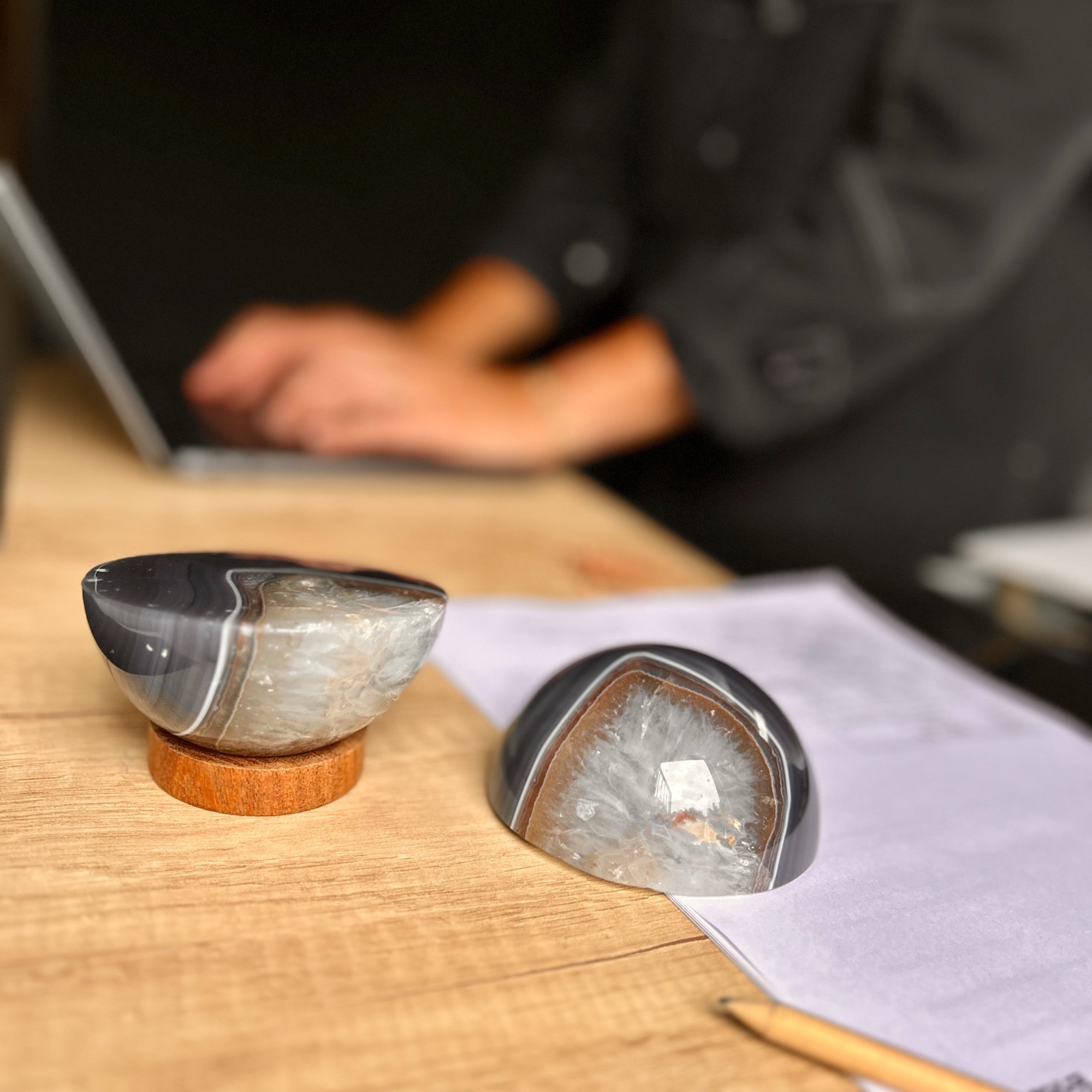 Two decorative items on a wooden surface with a blurred person in the background.